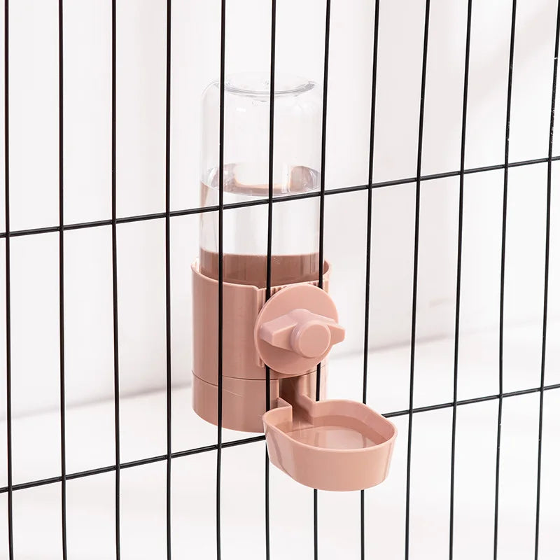 Clip-on pet feeder with automatic gravity water bottle, pink pet water bottle and feeder set against a black grid background.