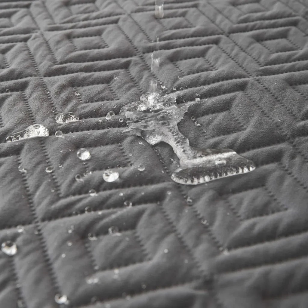 Close-up of a textured black surface with water droplets - Close-up of water spill proof protecting furniture from spills
